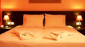 A hotel room with a large bed, two bedside lamps, and a framed artwork on the wall. - Blue Harmony Apartments (Naxos)