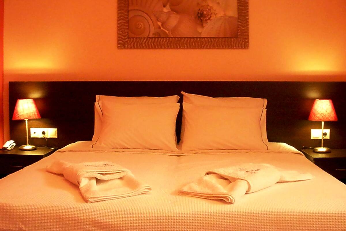 A hotel room with a large bed, two bedside lamps, and a framed artwork on the wall.