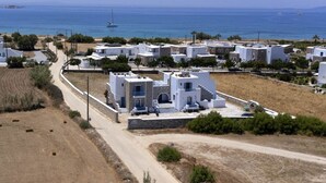 A coastal village with white buildings, a dirt road, and a view of the sea. - Blue Harmony Apartments (Naxos)