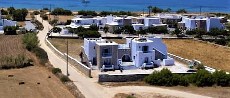 A coastal village with white buildings, a dirt road, and a view of the sea.
