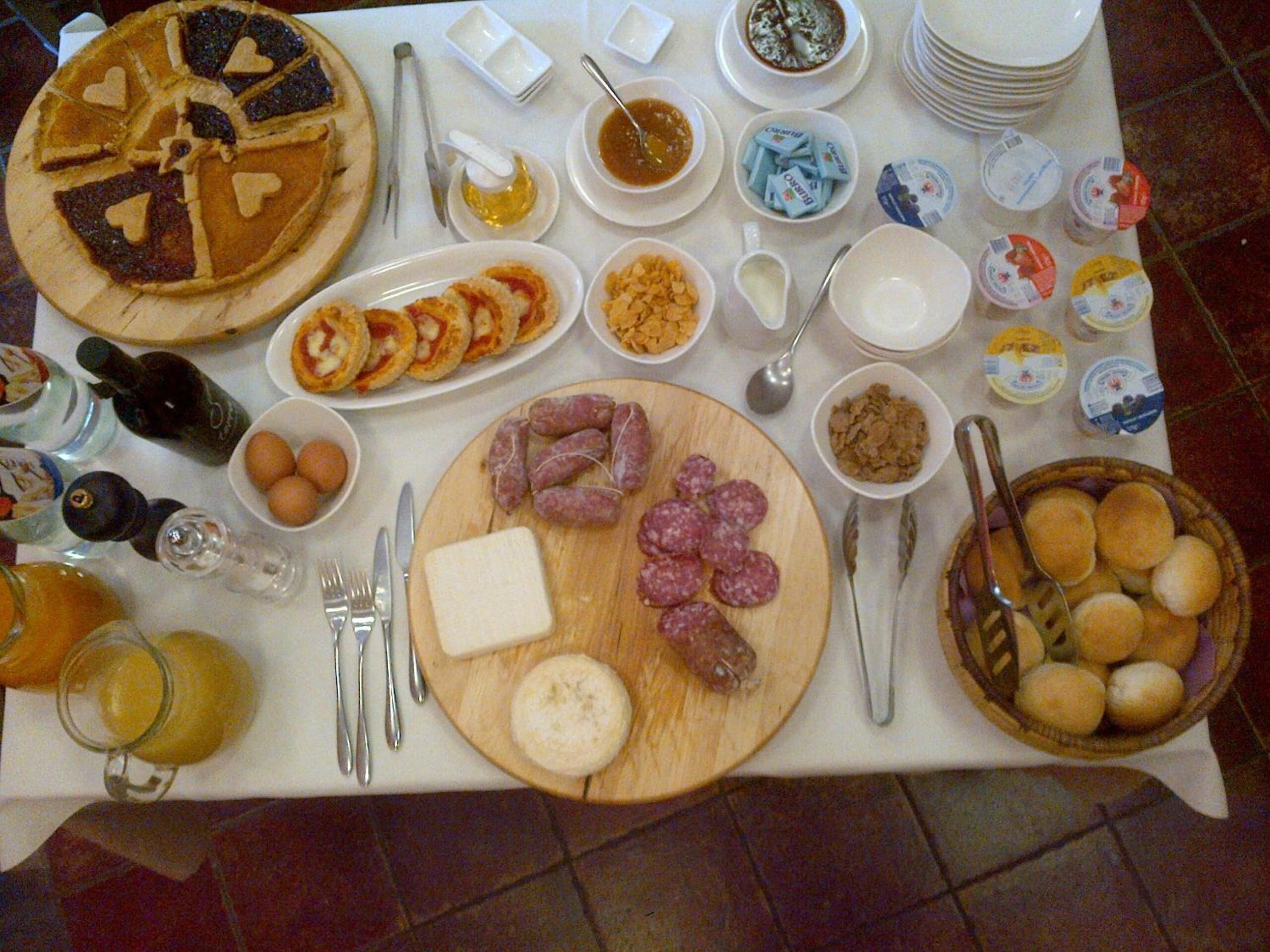 A table with various food items, including a large pie, sliced meats, and condiments.