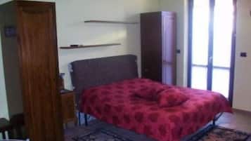 Une chambre à coucher comprenant un lit, une armoire, une table de chevet et une fenêtre avec des rideaux.