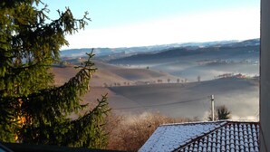 A view of a rural landscape with rolling hills, a clear sky, and a distant village. - L'Angolo di Rosina (Novello)