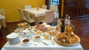 A breakfast buffet with various dishes, including pastries, meats, and beverages, set on a table with a white tablecloth.