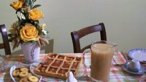 A dining table with a waffle, a pitcher of coffee, and a vase of flowers. - L'Angolo di Rosina (Novello)