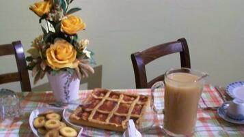Una mesa de comedor con un gofre, una jarra de café y un jarrón con flores.