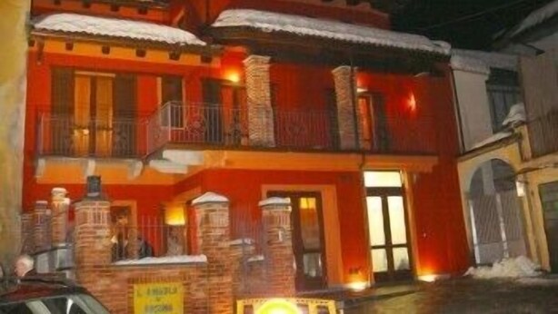 A two-story building with a red facade, multiple balconies, and a sign indicating a restaurant. - L'Angolo di Rosina (Novello)