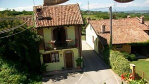 A rural street with houses featuring tiled roofs and a central building with a balcony.