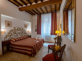 Una camera da letto con un letto, una sedia, un tavolo, un termosifone e delle tende.