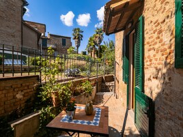 Un cortile con un tavolo piastrellato, piante in vaso e un muro in mattoni.