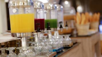 A beverage dispenser with multiple colored options, a tray of glasses, and a basket of bread.