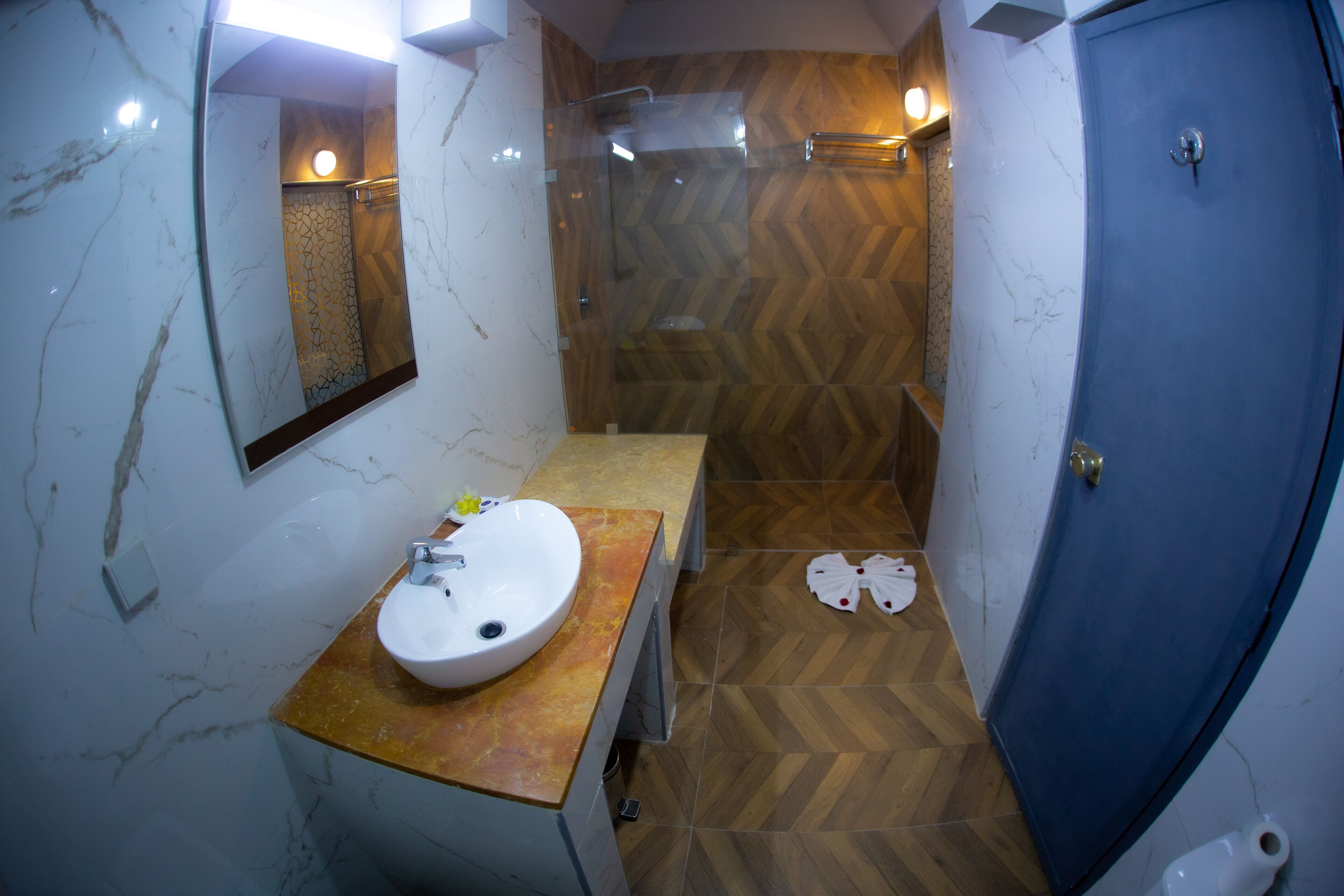 A bathroom with a marble sink, wooden vanity, and a shower with a herringbone floor pattern.