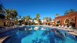 Una piscina con sillas de descanso y palmeras.