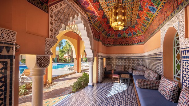 Un interior tradicional marroquí con elaborados trabajos en azulejos, una piscina y un área de estar.