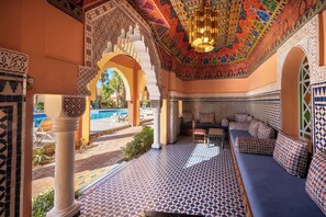 Un interior tradicional marroquí con elaborados trabajos en azulejos, una piscina y un área de estar.