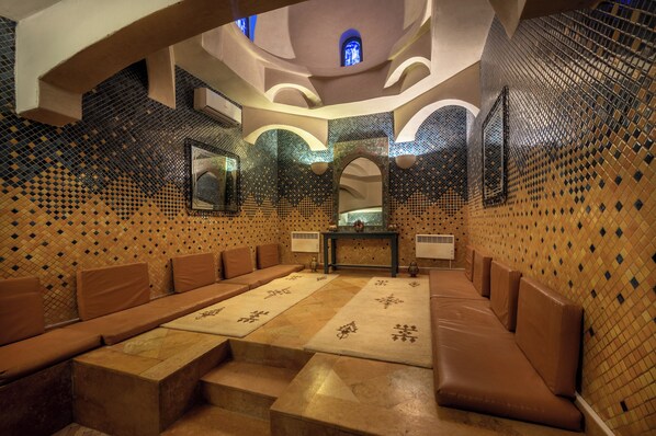 A spa room with a long bench, a small table, and a mirror on the wall. - Hotel Karam Palace (Ouarzazate)