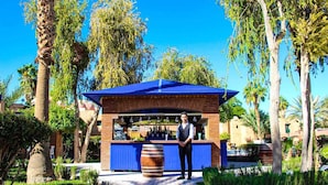 Una zona de bar con techo azul, un cantinero y una barra de ladrillo.