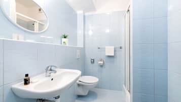 Un baño moderno con lavamanos, inodoro y ducha.