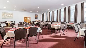A large conference room with multiple tables and chairs, arranged in rows.