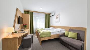 Una habitación de hotel con cama, escritorio, silla, sofá y televisión.