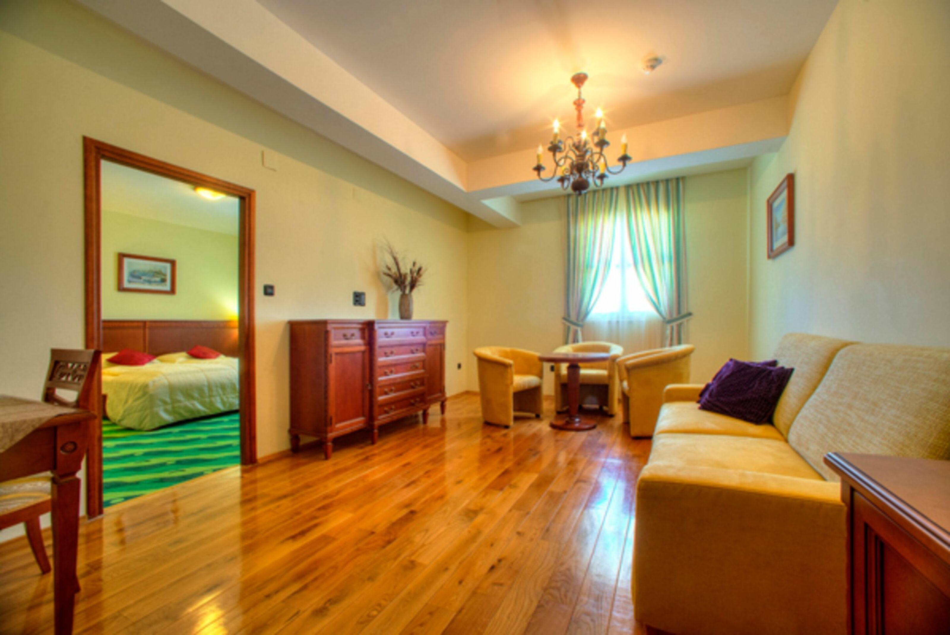 Een kamer met een bed, een houten dressoir, een bank en een eettafel.