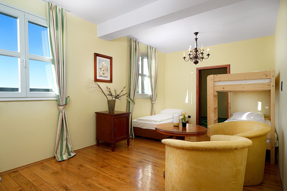 Ein Zimmer mit einem Etagenbett, einem Holztisch, einem Stuhl, einem kleinen Tisch mit einer Vase und einer Kristallleuchter.
