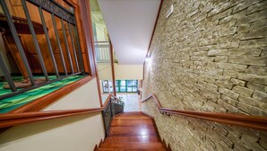 Una escalera de madera con un muro de ladrillo a un lado y una barandilla al otro.