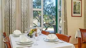 Mesa para cuatro cubierta con mantel blanco, platos y cubiertos.