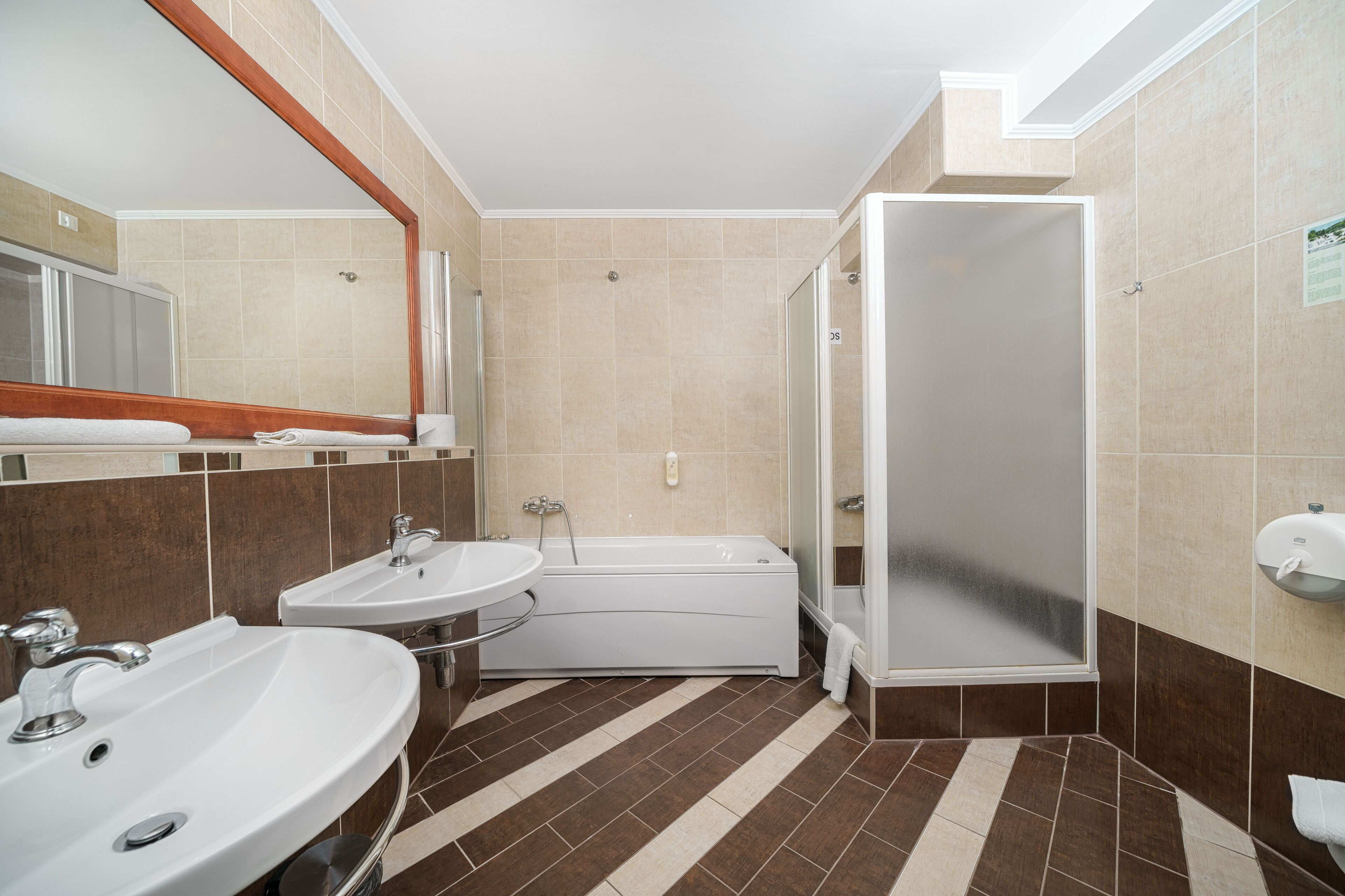 Un baño con dos lavamanos, una bañera y una ducha.