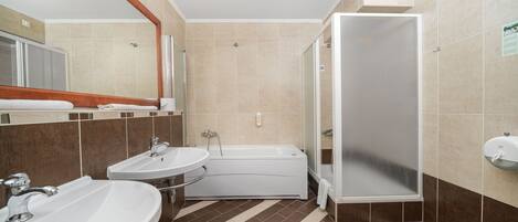 A bathroom with two sinks, a bathtub, and a shower.
