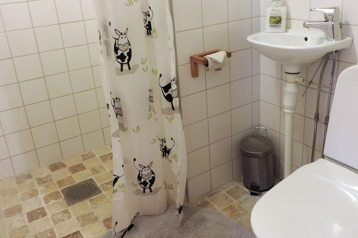 A bathroom with a toilet, sink, and a shower curtain with cow patterns.