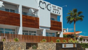 A modern hotel with a white facade, wooden accents, and a sign for 'San Jose Hotel'. - MC San José (Nijar)