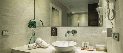 A modern bathroom with a large mirror, a white sink, and a hairdryer mounted on the wall.