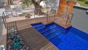 A swimming pool with wooden deck and steps leading into it. - MC San José (Nijar)