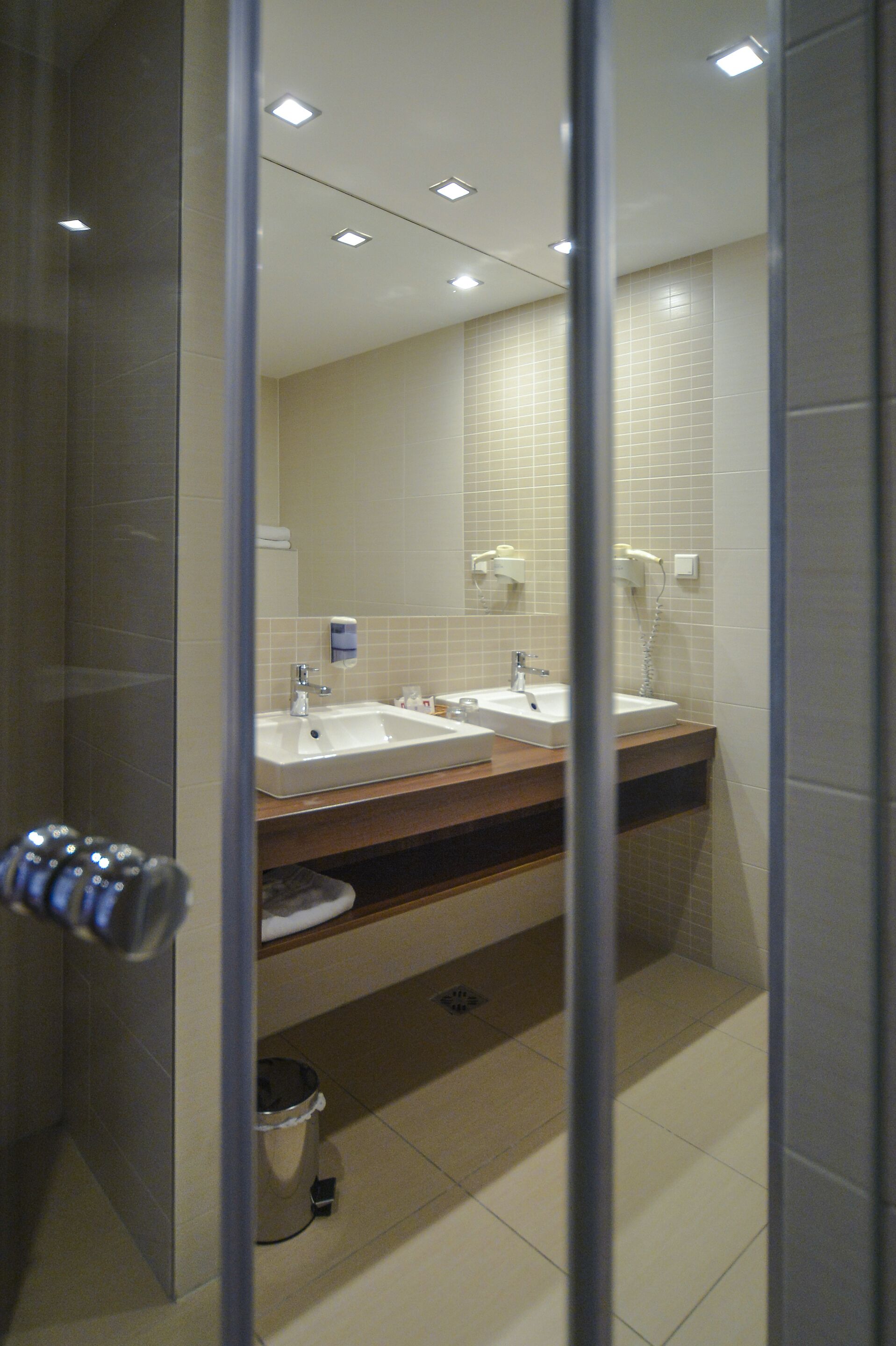 Une salle de bain moderne avec deux lavabos, un miroir et un espace douche.
