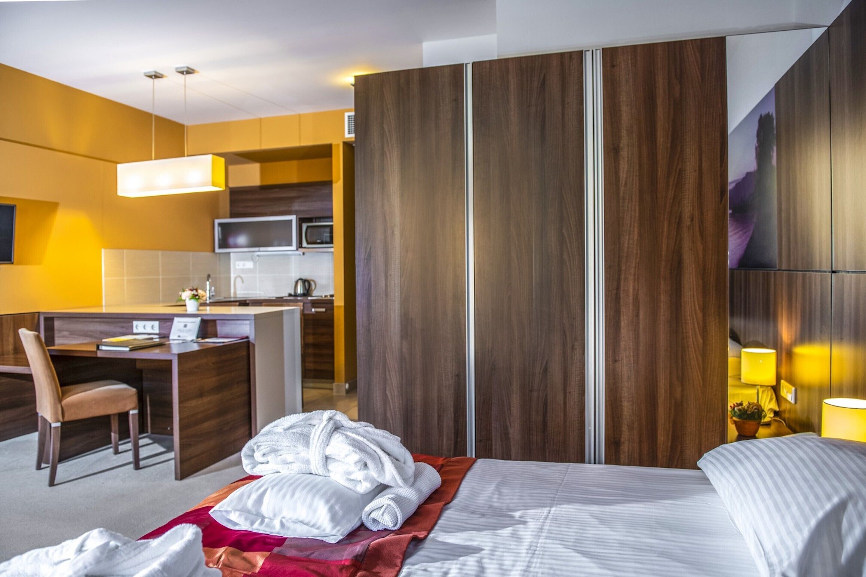 Ein Hotelzimmer mit Bett, Schreibtisch, Stuhl, Mikrowelle und Kleiderschrank.
