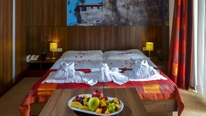 A hotel room with a bed, a fruit platter, and a painting on the wall. - Royal Club Hotel (Visegrád)