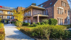 A modern hotel with a brick facade, a covered outdoor area, and a paved walkway. - Royal Club Hotel (Visegrád)