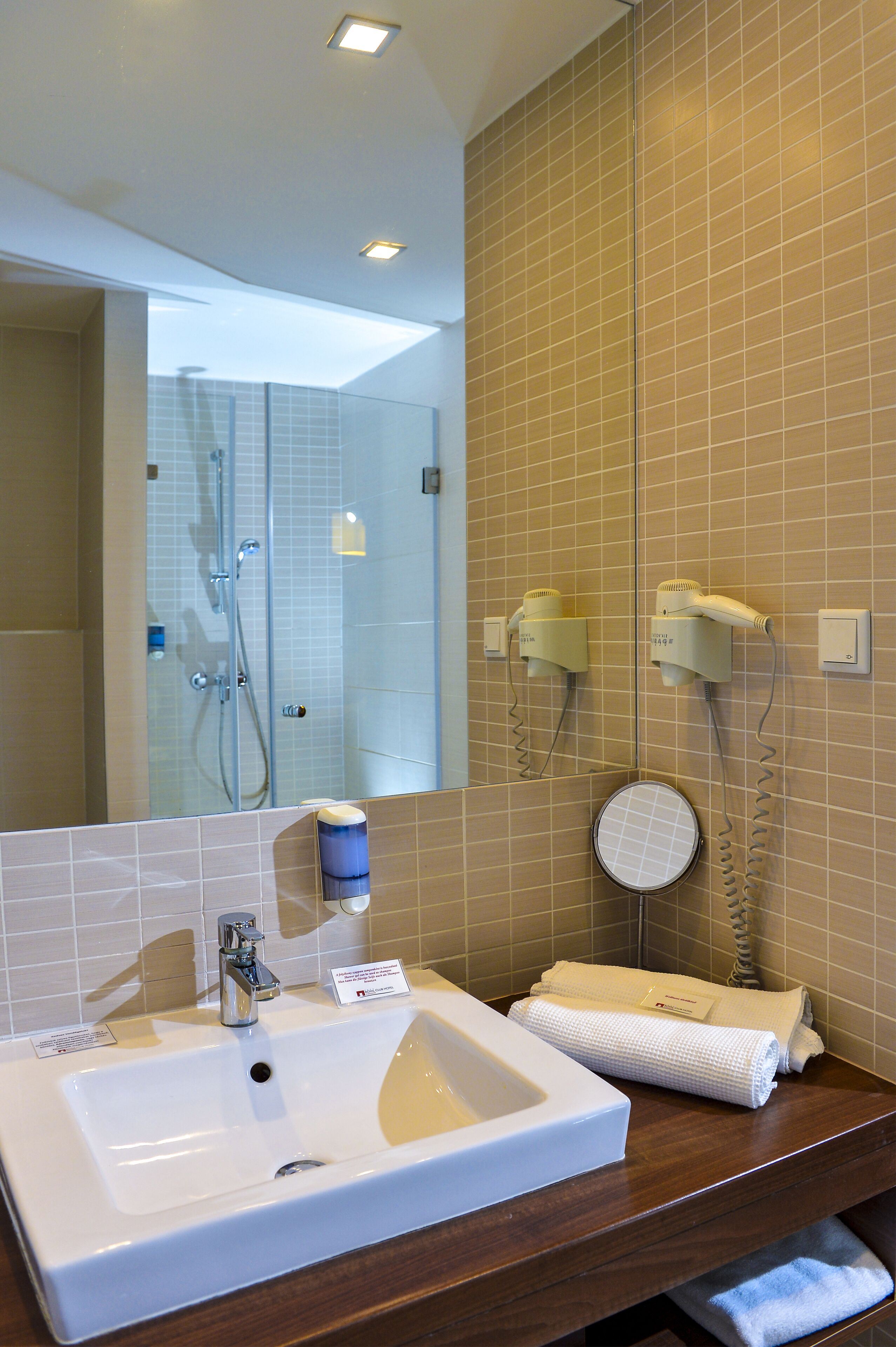 Un baño con un espejo grande, un lavabo, una toalla y un secador de pelo montado en la pared.