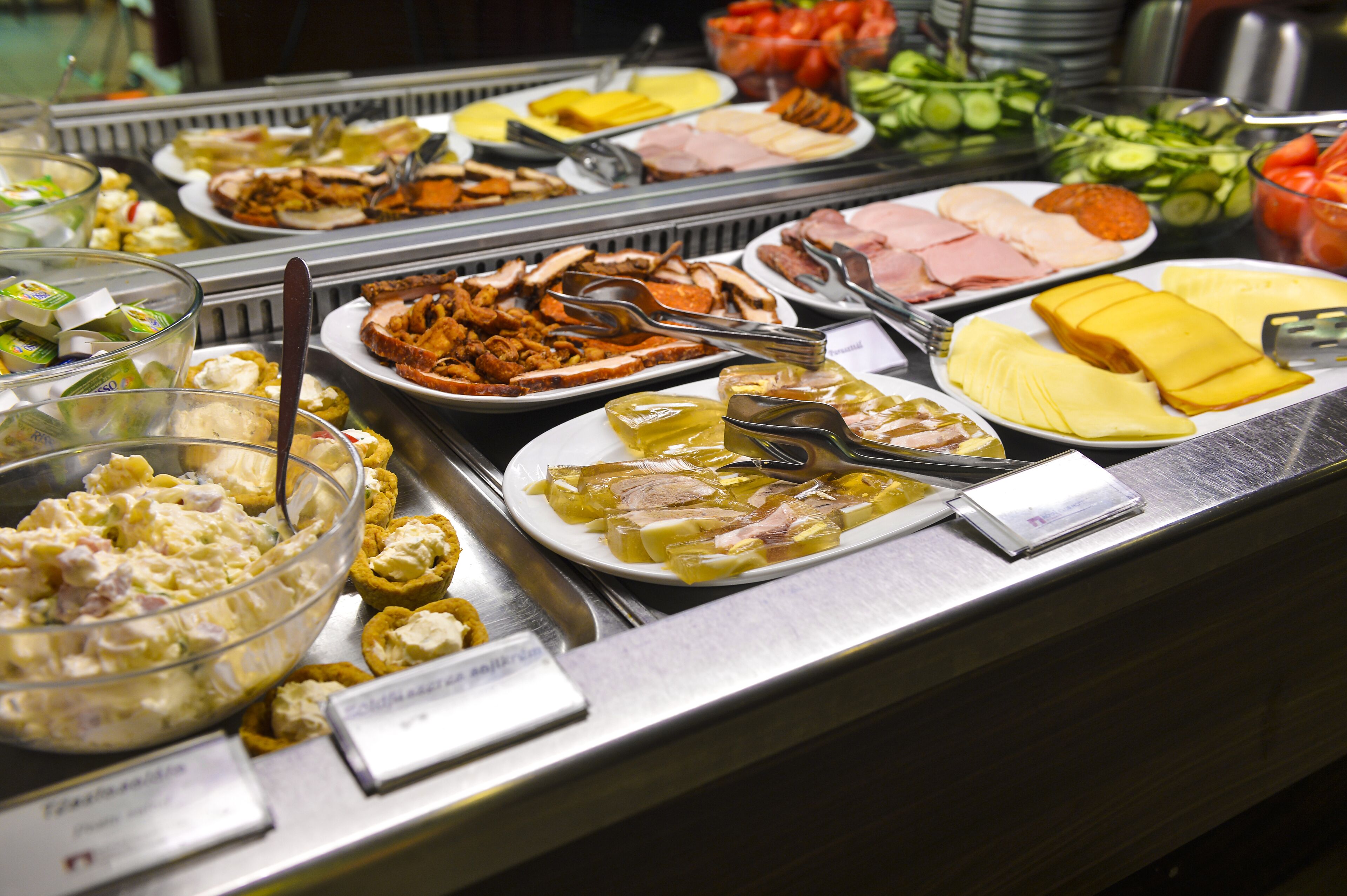 Un bufé con diferentes opciones de comida, incluyendo ensaladas, carnes y quesos.