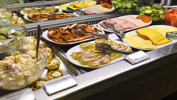 Un bufé con diferentes opciones de comida, incluyendo ensaladas, carnes y quesos.