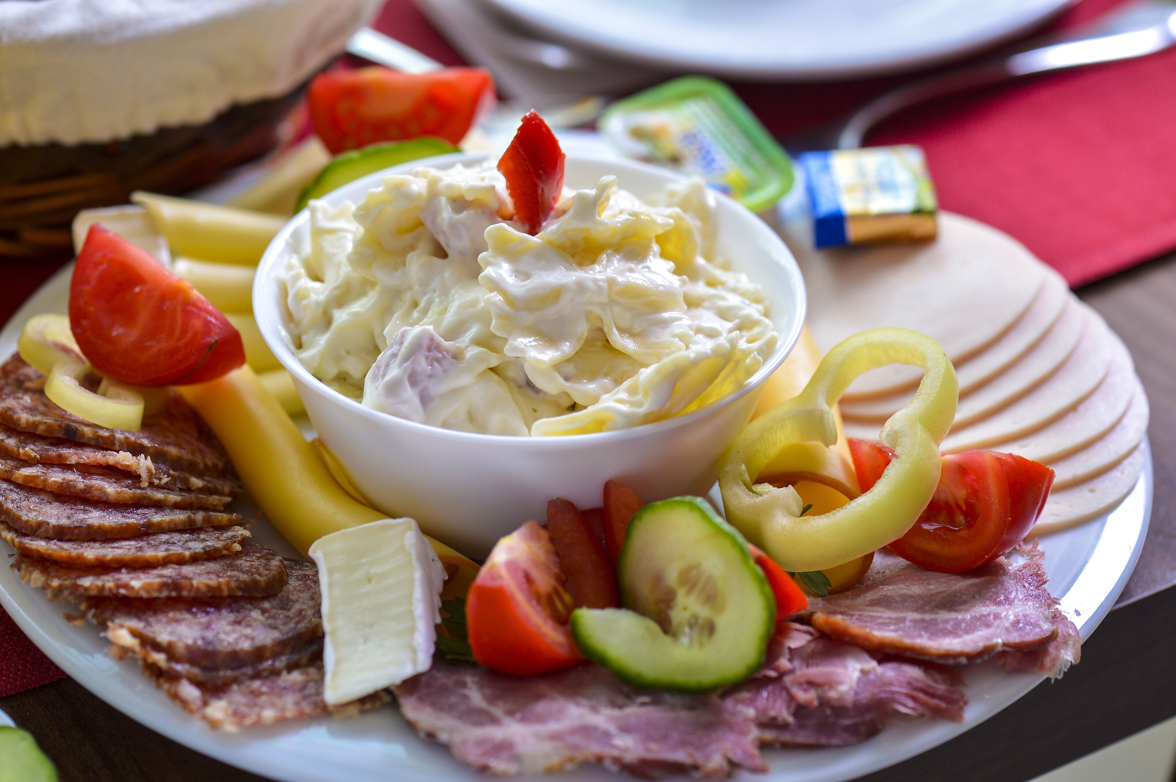 Un plato con diversos alimentos, incluyendo carnes cortadas, queso y verduras.