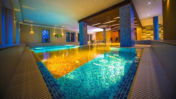 A large indoor swimming pool with a tiled floor and a view of the surrounding area. - Royal Club Hotel (Visegrád)