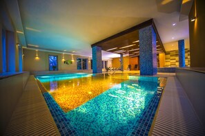 A large indoor swimming pool with a tiled floor and a view of the surrounding area. - Royal Club Hotel (Visegrád)
