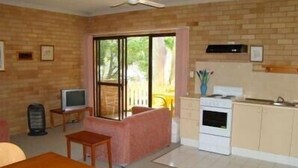 A compact living space with a kitchenette, a dining area, and a large window providing natural light.