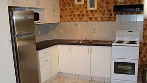 A kitchen with white cabinets, a stainless steel refrigerator, a stove, and a microwave.