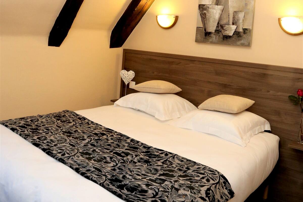 Ein Schlafzimmer mit einem Bett, einem Holz-Kopfteil, einem Wandbild und zwei Wandleuchten.