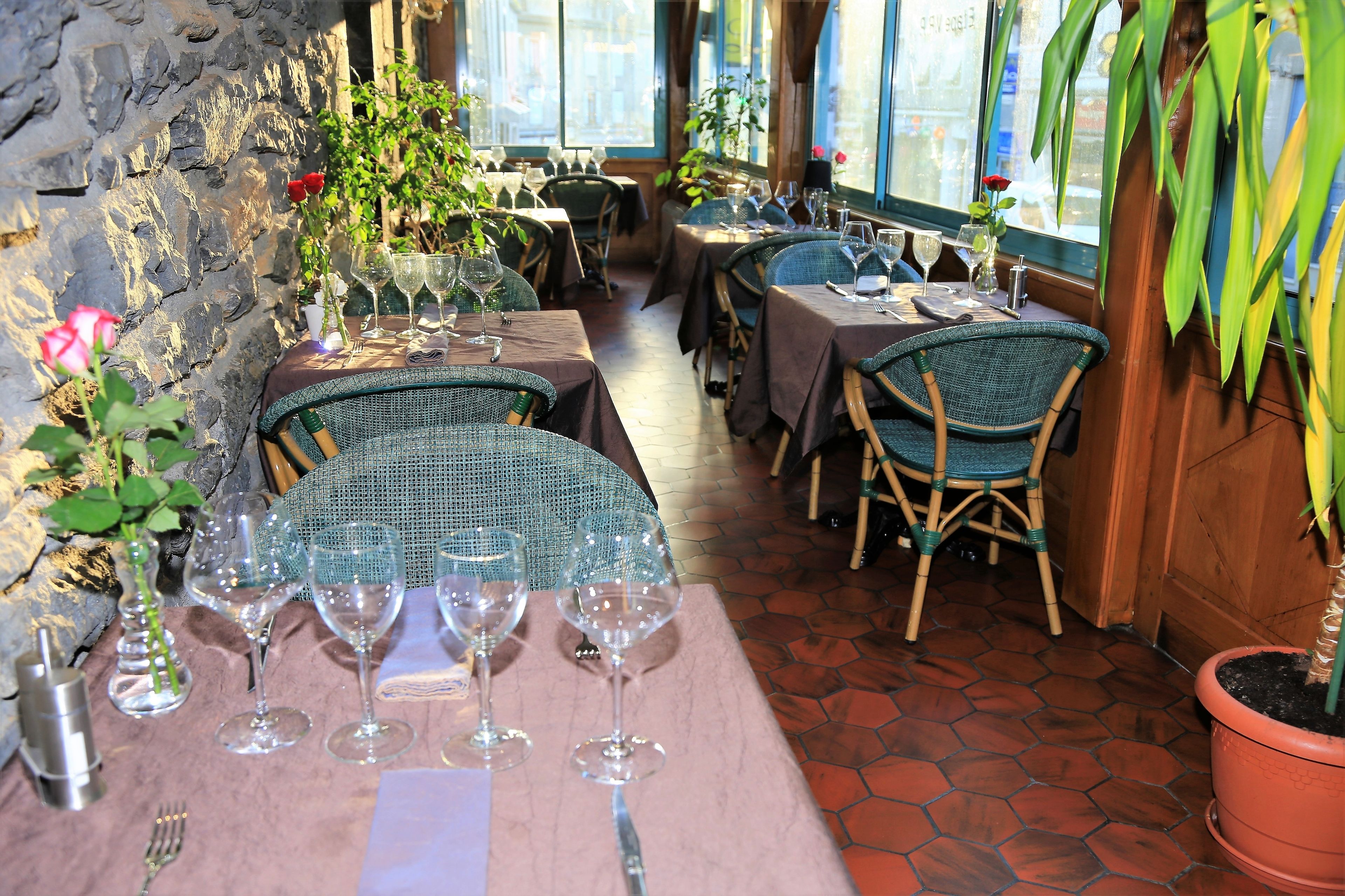 A restaurant with stone walls, wicker chairs, and tables set for dining.