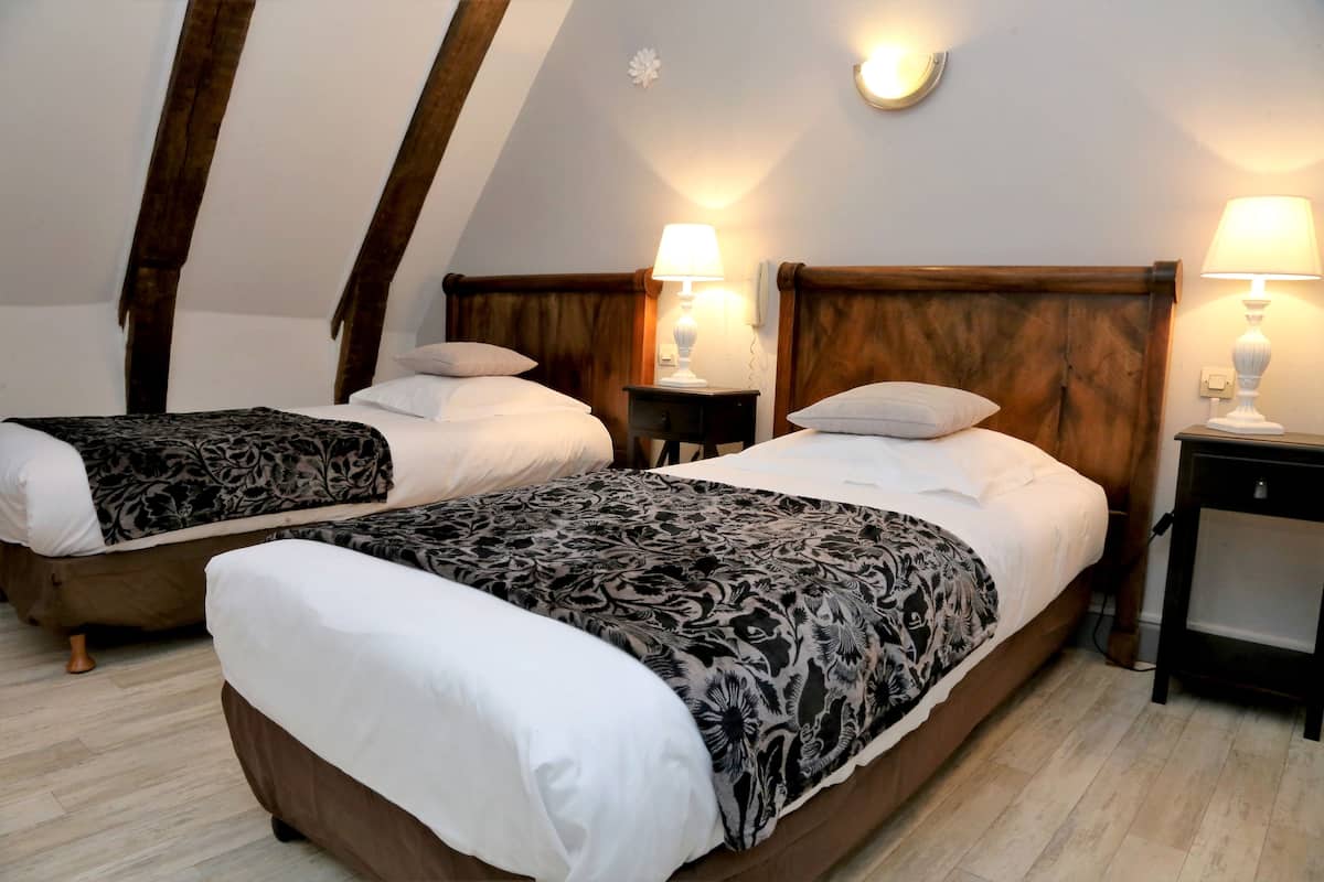 Ein Zimmer mit zwei Betten, Holz-Kopfteilen, Nachttischlampen und Holzboden.