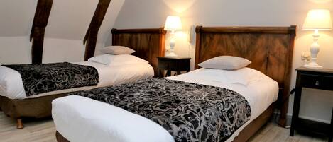 Quarto com duas camas, cabeceiras de madeira, luminárias de apoio e piso de madeira.